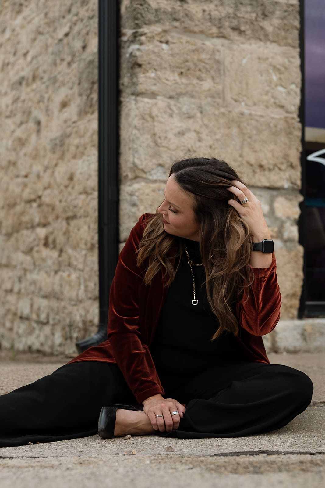 Molly Knuth sits on a sidewalk corner and runs her fingers through her hair.