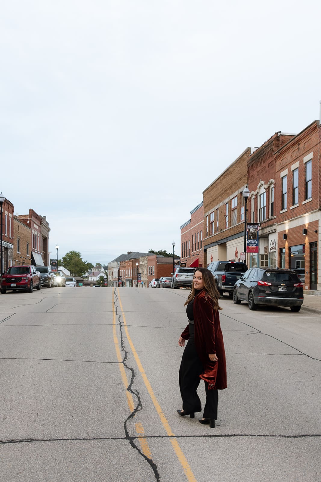Molly standing in the middle of a downtown street with brick storefronts and cars on either side.